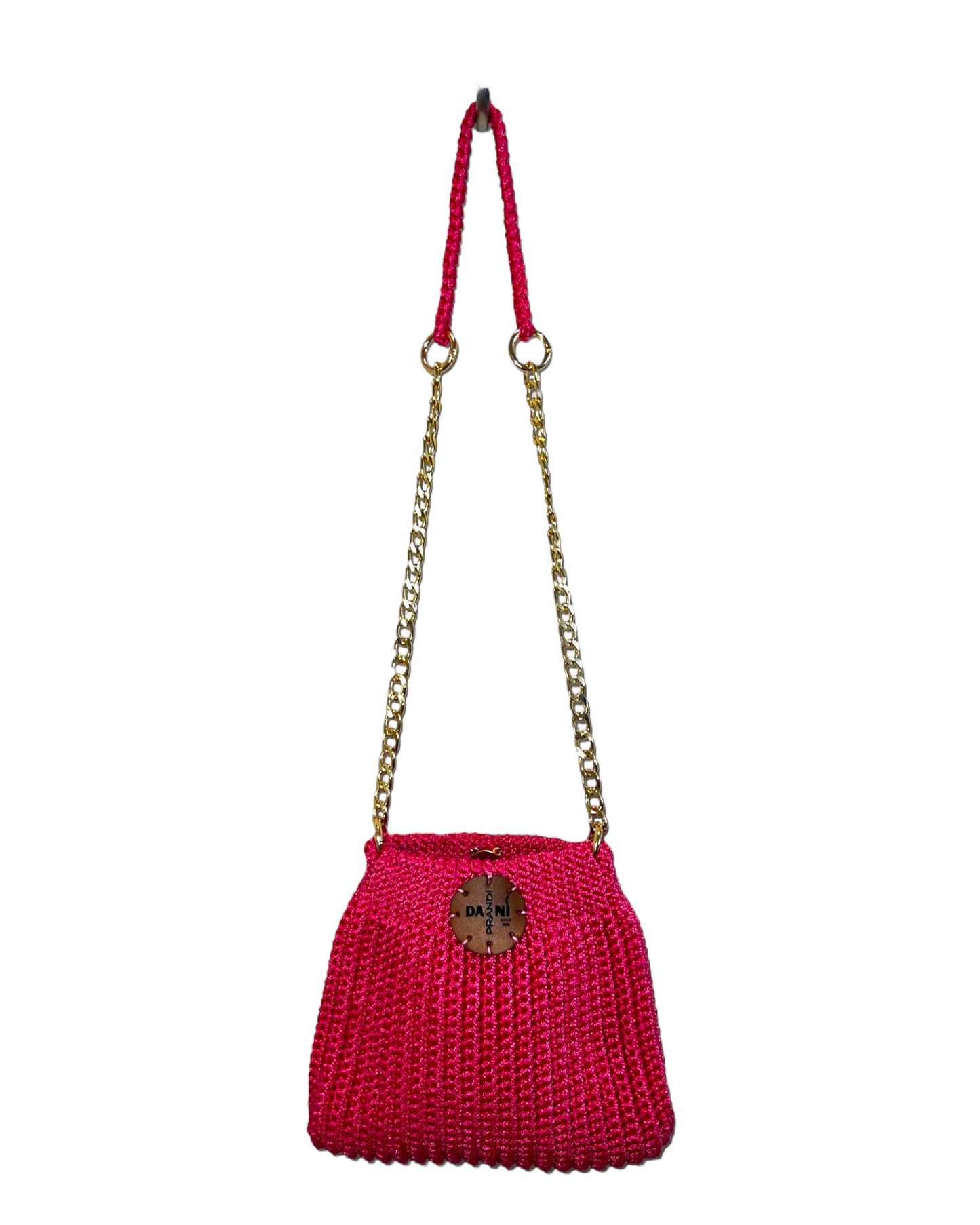 mini pouch-style embroidered crochet bag in a striking fuchsia color. The intricate embroidery adds artistic flair to the design, elevating it beyond a simple accessory. The golden metal chain provides a touch of chic versatility, allowing the bag to be worn effortlessly over the shoulder or crossbody. The upper part of the chain, crafted from the same fabric as the bag, ensures both elegance and comfort during wear.