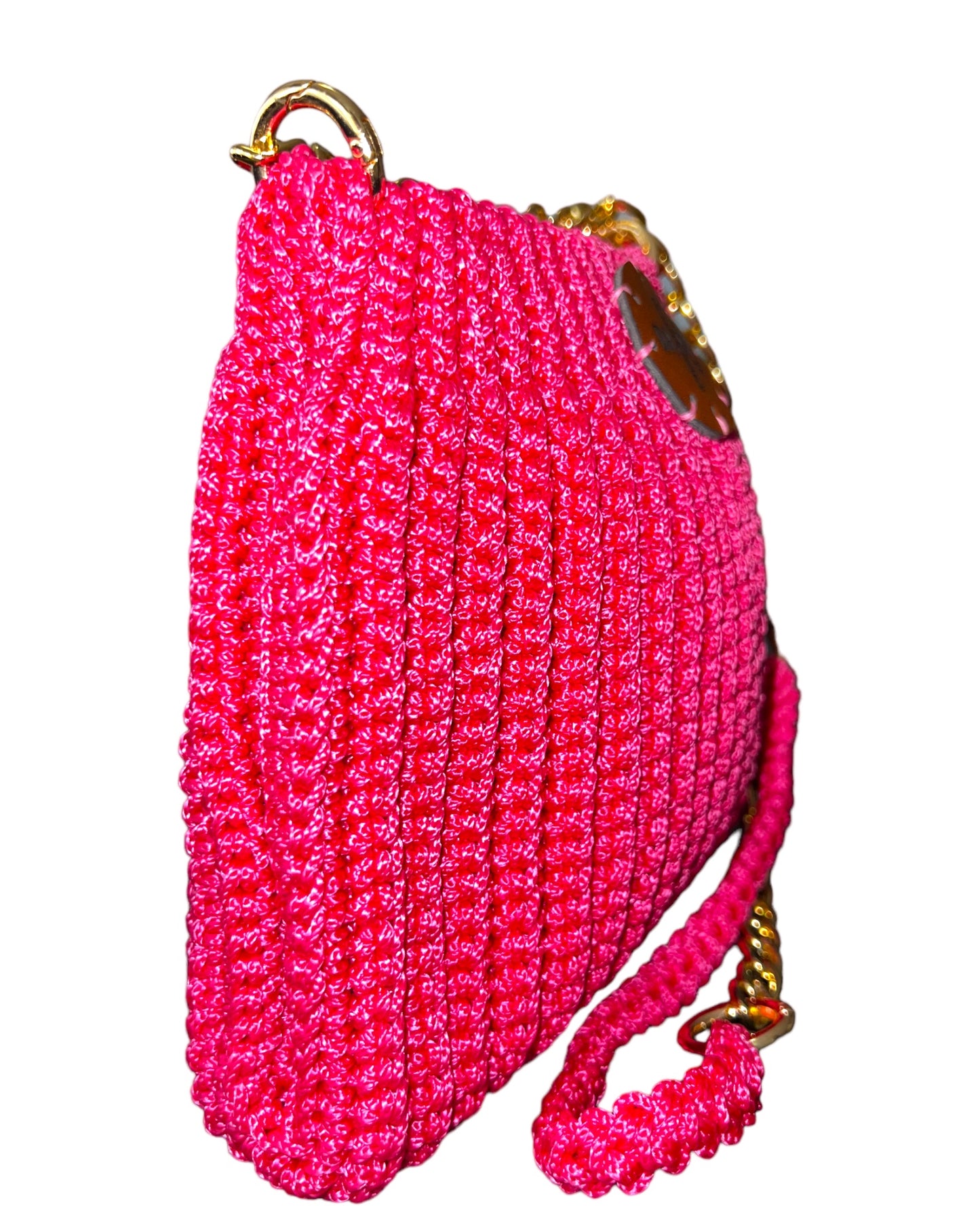 mini pouch-style embroidered crochet bag in a striking fuchsia color. The intricate embroidery adds artistic flair to the design, elevating it beyond a simple accessory. The golden metal chain provides a touch of chic versatility, allowing the bag to be worn effortlessly over the shoulder or crossbody. The upper part of the chain, crafted from the same fabric as the bag, ensures both elegance and comfort during wear.
