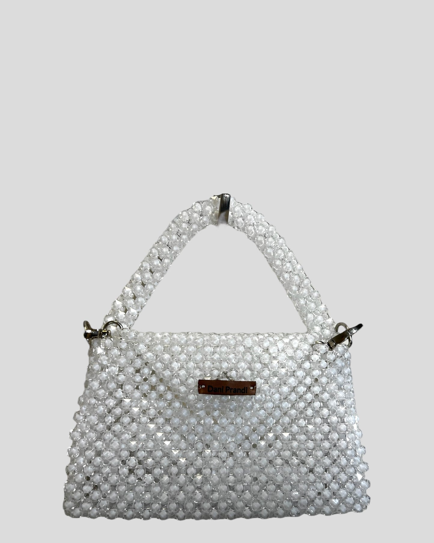 high-quality mini bag adorned with a delicate fake pearl border, exuding luxurious elegance. The bag comes with a removable shoulder strap made of the same material, offering versatile styling options. The transparent white color adds a timeless touch, making it an easy match for various looks.