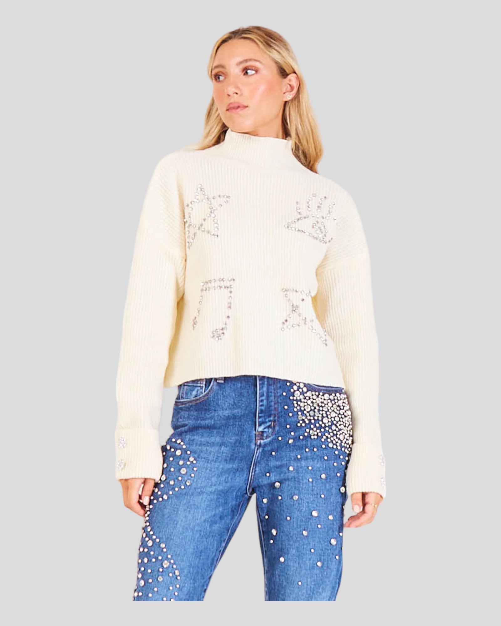 Sweater with a High Neck, Turn-Up Cuffs, and a Comfortable Straight Fit. The sweater is adorned with sparkling rhinestone applications on the front, and two large rhinestone buttons grace the turned cuffs, adding a touch of glamour. 